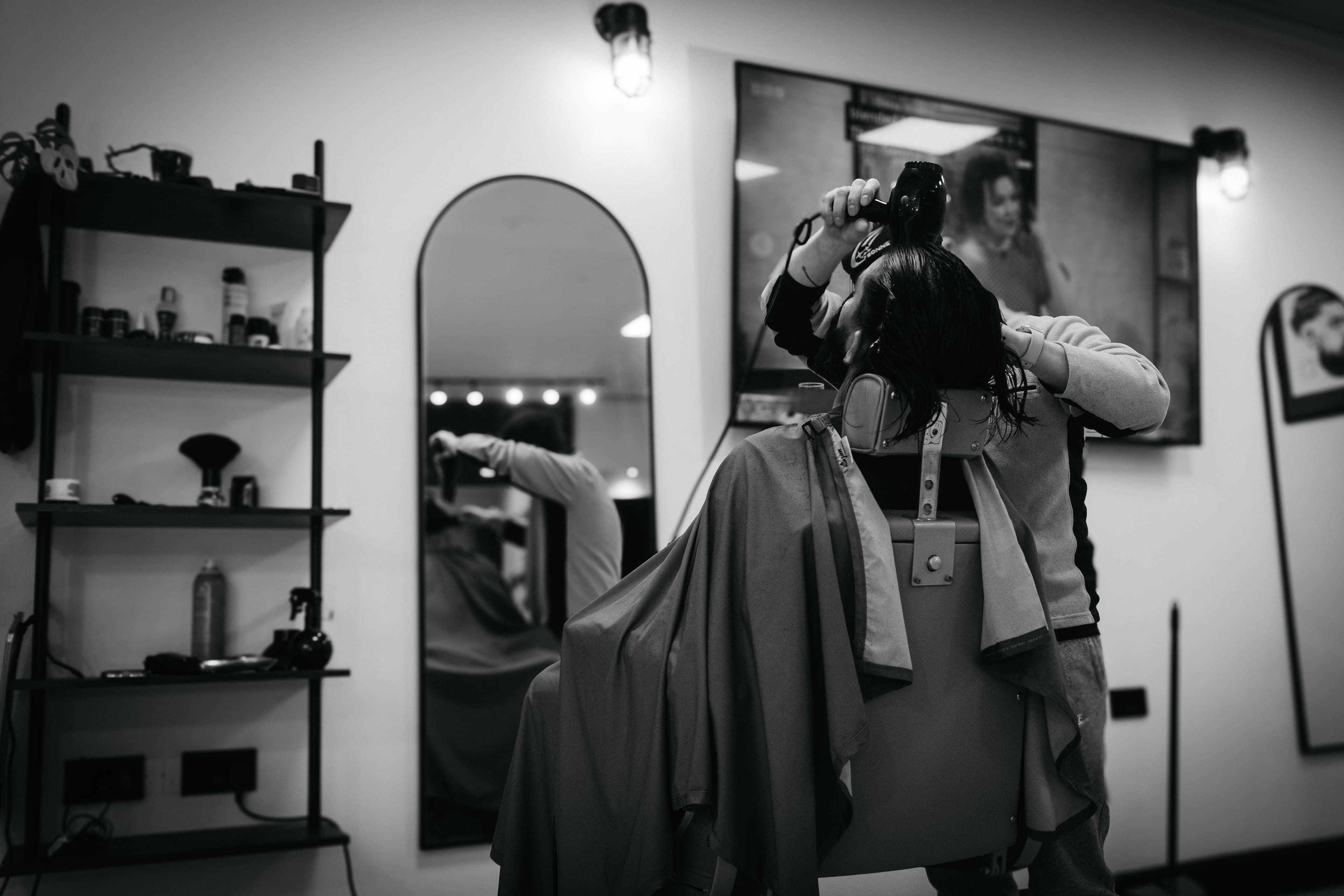 A barber at Drewrys mid-cut, framed by the arched mirror